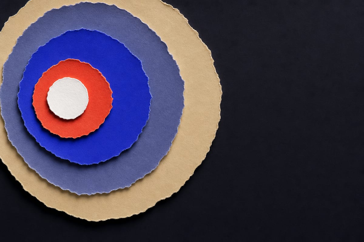 Four ragged concentric paper rings expanding outward from a small dense white disc
